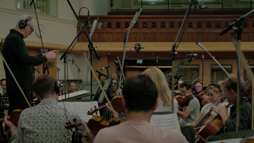 Conductor leads orchestra in recording studio