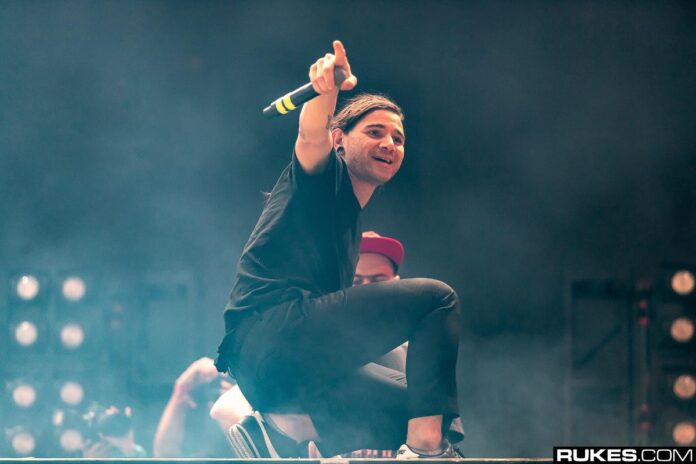 Skrillex performs, gesturing to crowd